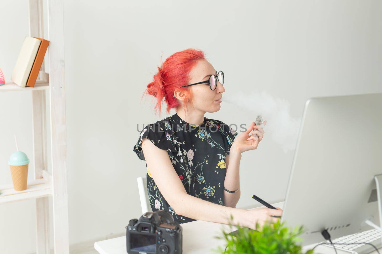 Creative, graphic designer, people concept - young creative woman smoking a vape while working in a graphic tablet.