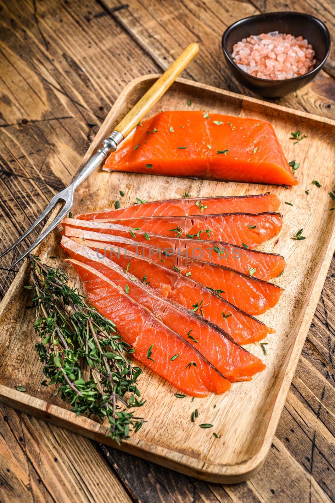 Salted salmon fillet slices in a wooden tray with thyme. wooden background. Top view by Composter