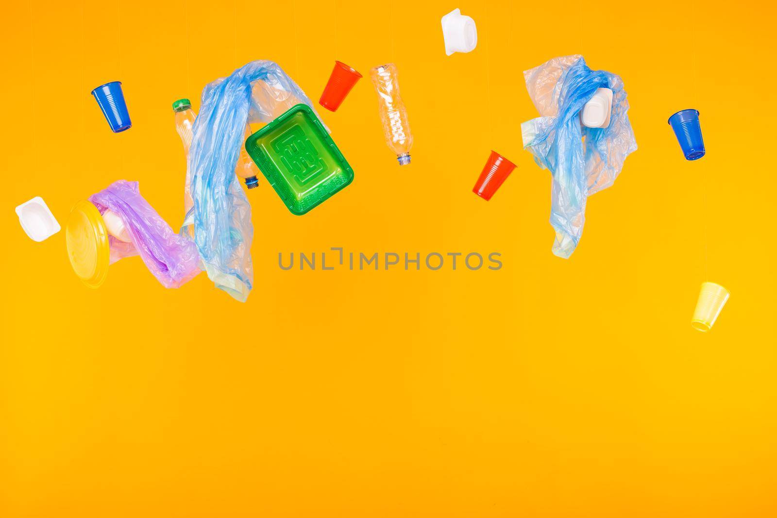Problem of trash, plastic recycling, pollution and environmental concept - plastic garbage on yellow background.