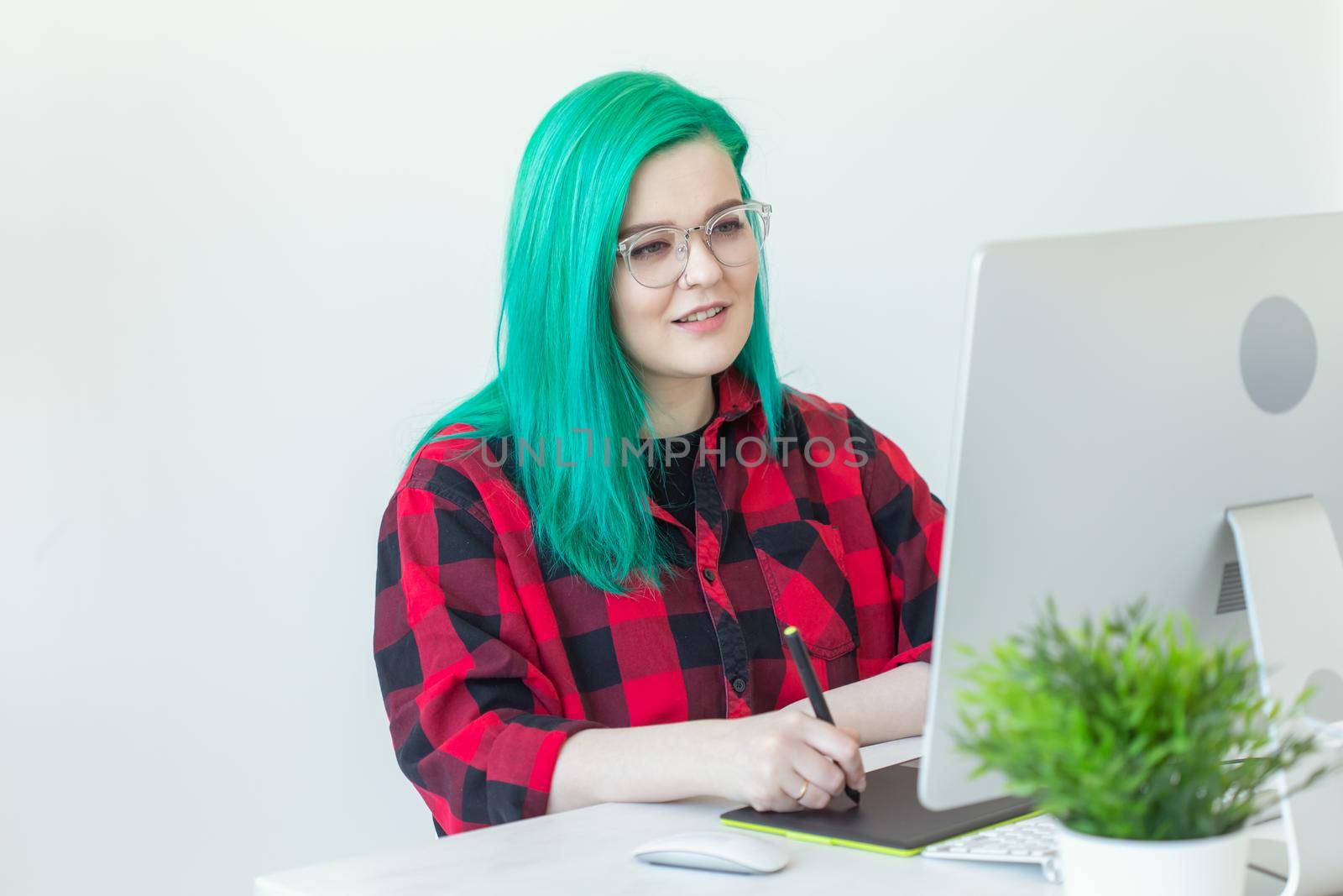 Graphic designer, animator and illustrator concept - young woman with green hair working at the laptop.