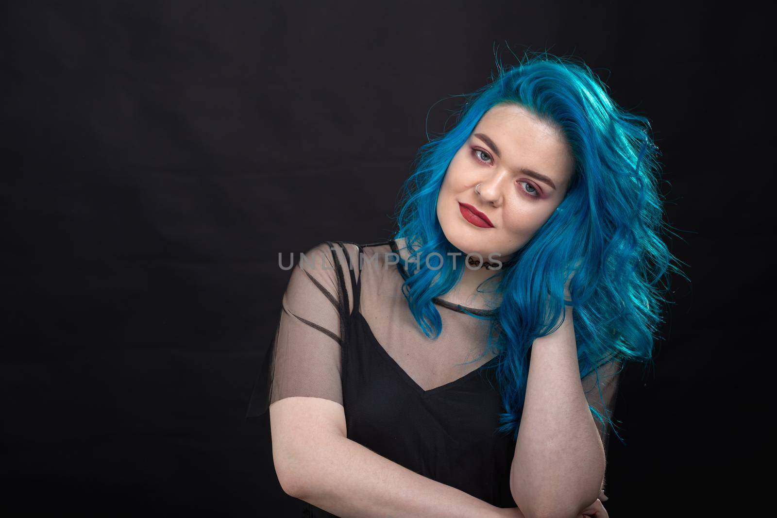Style and fashion concept - Young and attractive woman with blue hair posing over black background.