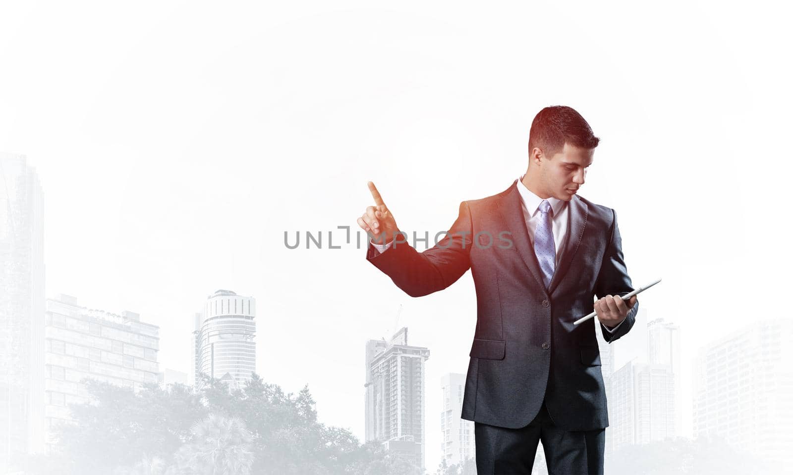 Businessman looking into documents and pointing away on white background. Front view of standing man in business suit and tie. Successful business person in formal wear gesturing with raised hand