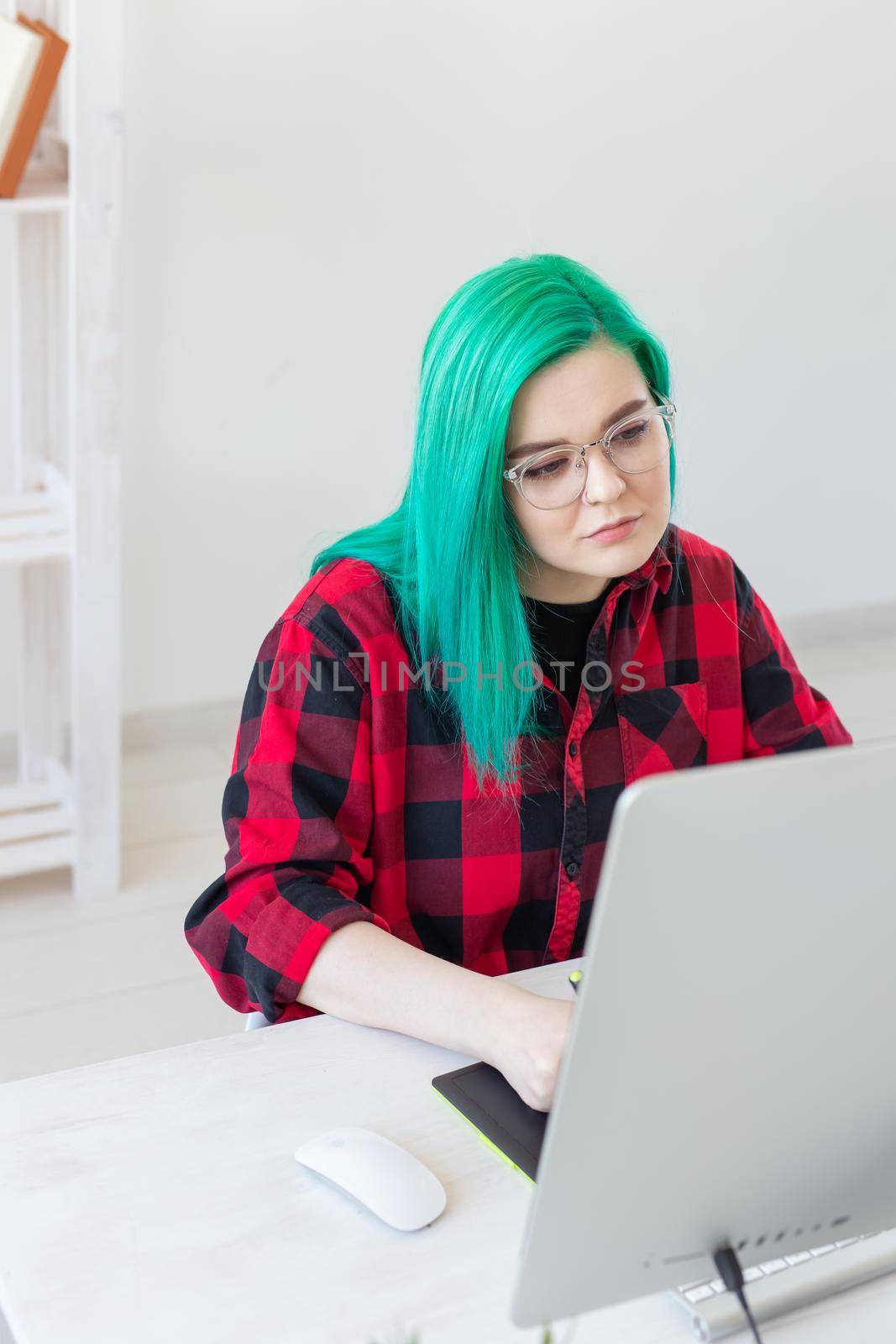 Creative, illustrator and designer concept - happy woman with green hair is drawing a project, vertical shot.