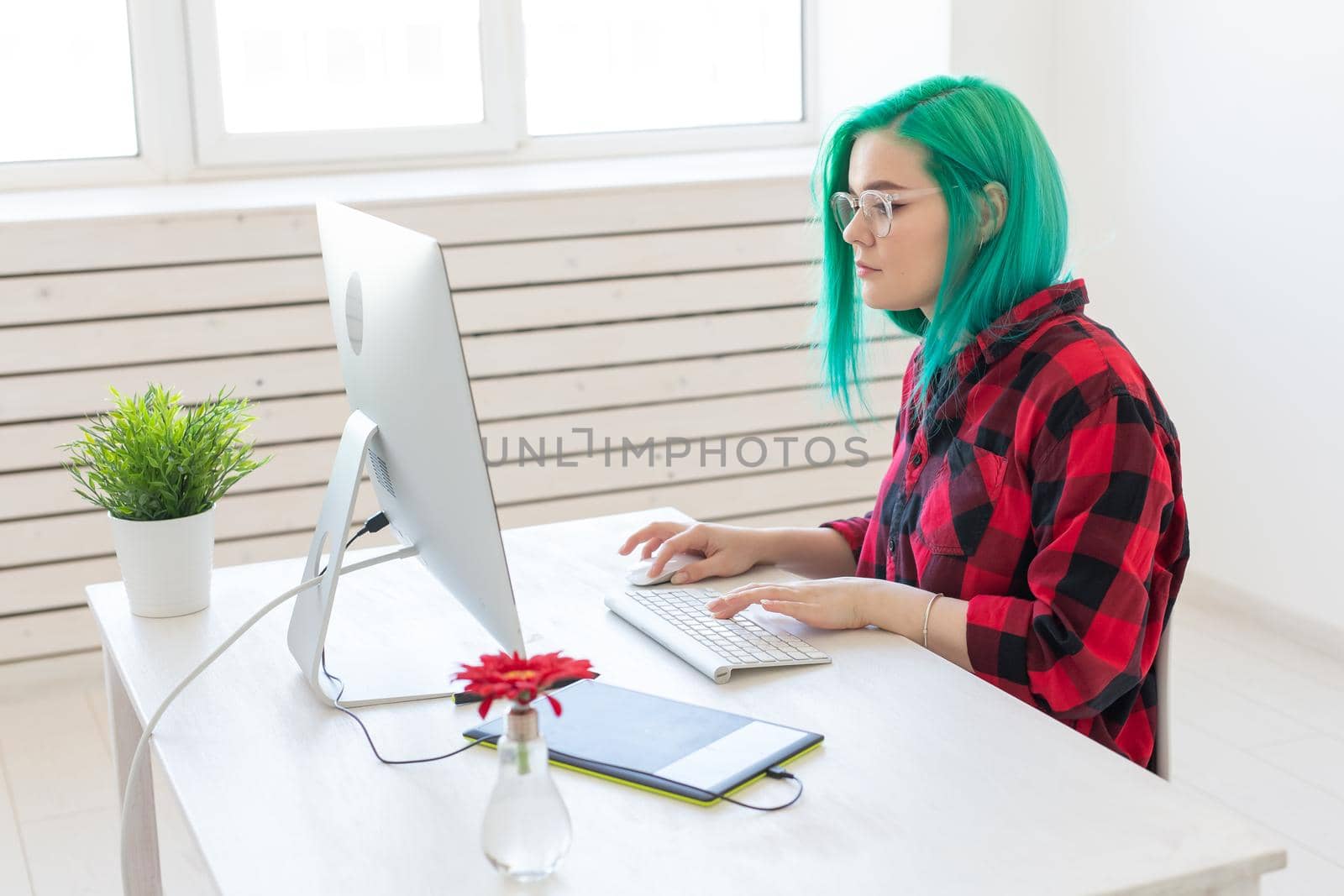Designer, creative, people concept - green hair woman designer doing a project on a graphic tablet.