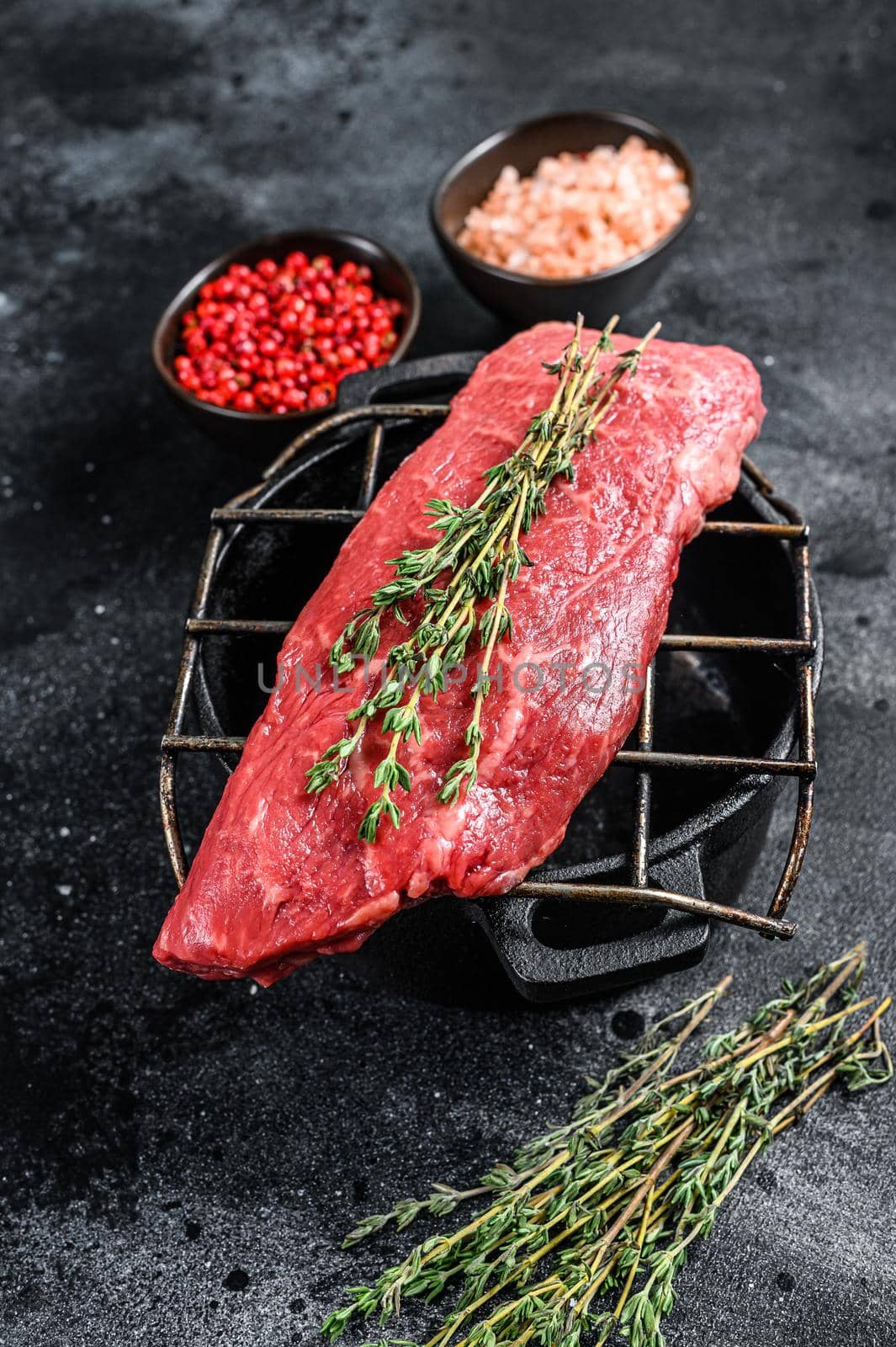 Raw Striploin steak on a grill, marbled beef. Black background. Top view by Composter