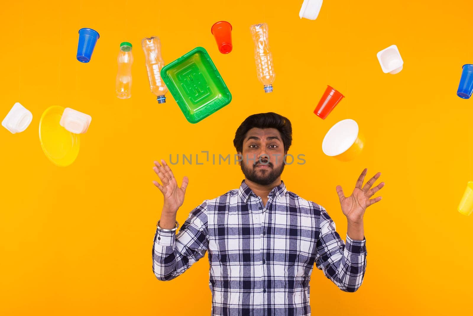 Environmental pollution, plastic recycling problem and ecology problem concept - sad indian man is upset because is got too much of plastic on the planet on yellow background