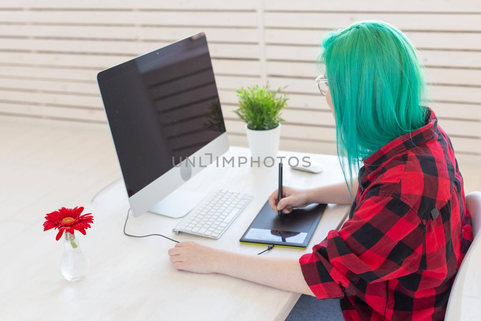 Graphic designer, people concept - Young designer female hipster with graphic tablet working in office.