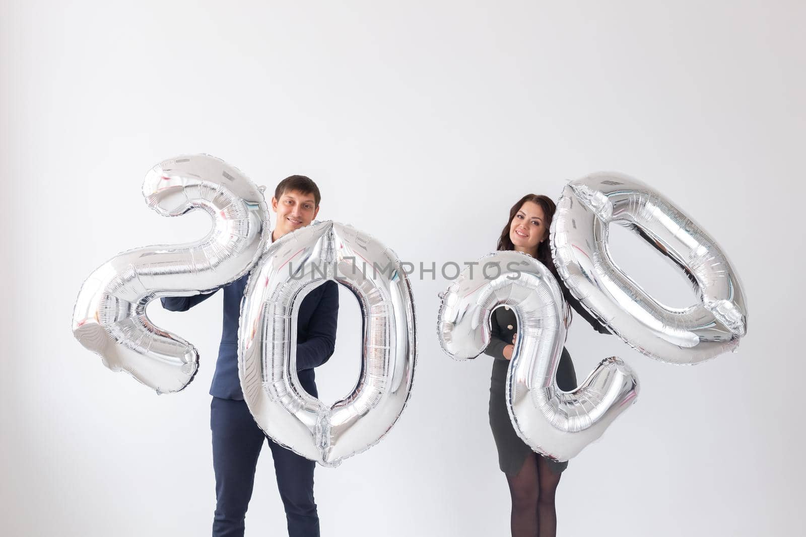 New year, celebration and holidays concept - love couple having fun with sign 2020 made of silver balloons for new year on white background by Satura86