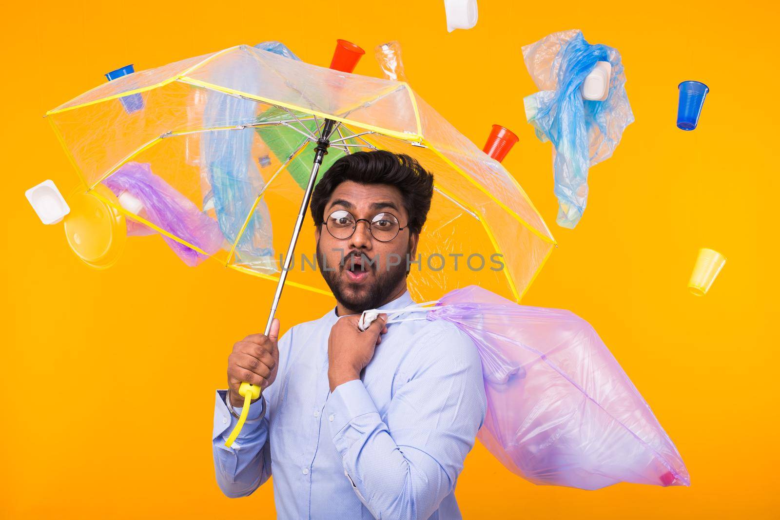 Problem of trash, plastic recycling, pollution and environmental concept - man carrying garbage bag on yellow background.
