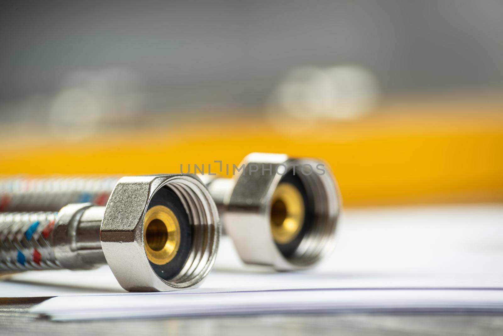 Flexible steel water hoses laying on table. Close up water fittings and connections with segments of braided hose. Plumbing supply shop advertising. house hydraulic infrastructure installation.