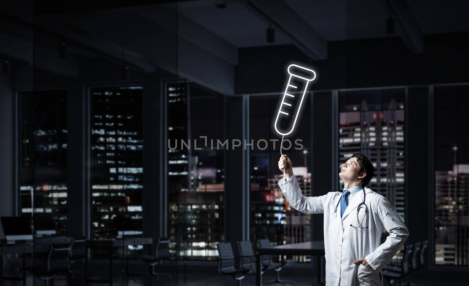 Horizontal shot of young confident doctor in white medical uniform interracting with glowing vial symbol whie standing against night cityscape view on background.