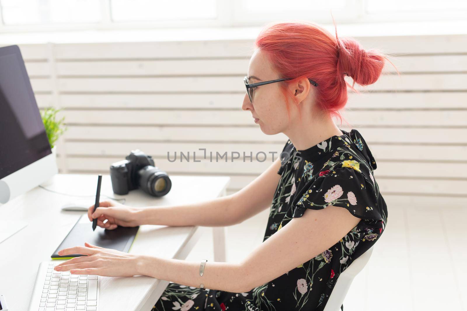 Illustrator, graphic designer, animator and artist concept - creator woman with beautiful red hair and glasses drawing in laptop.