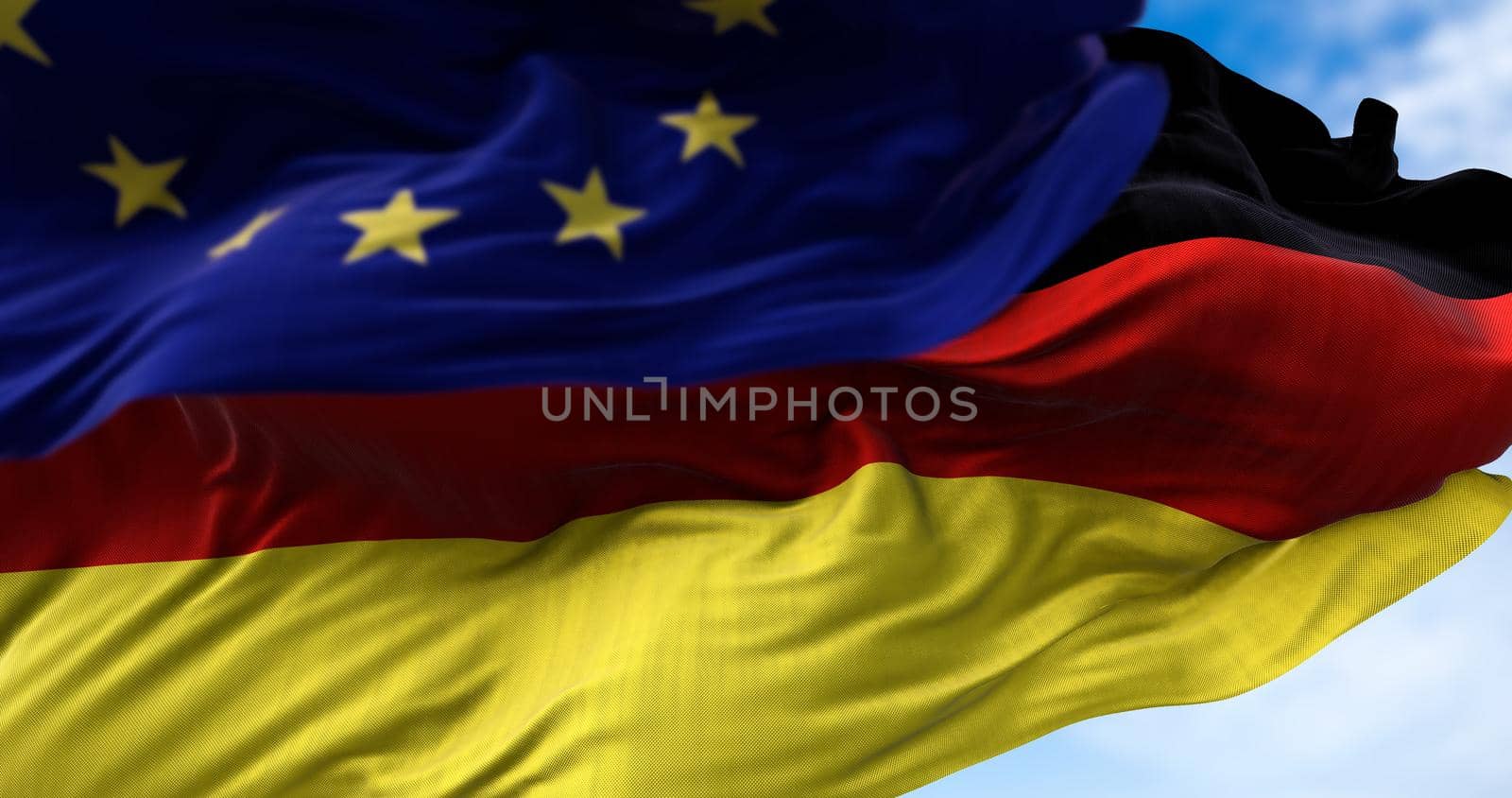 The national flag of Germany waving in the wind together with the European Union flag blurred in the foreground by rarrarorro