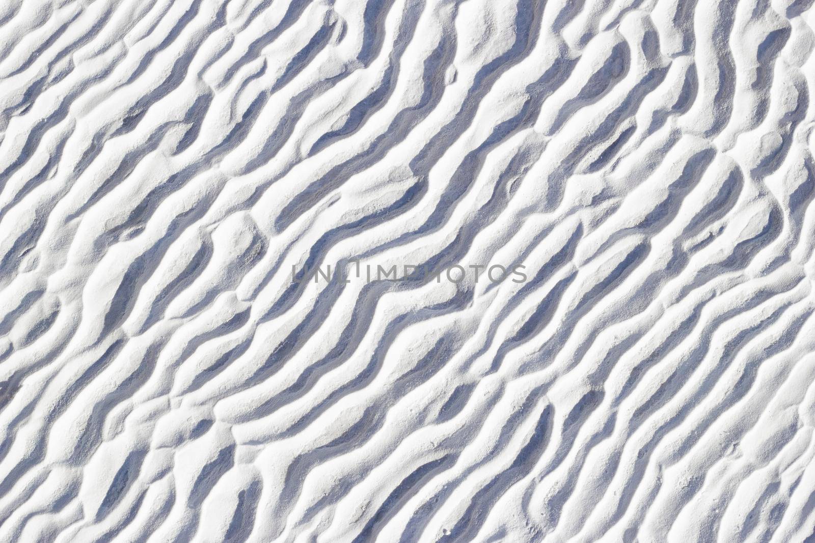 White texture of Pamukkale calcium travertine in Turkey, pattern of diagonal waves, close-up.