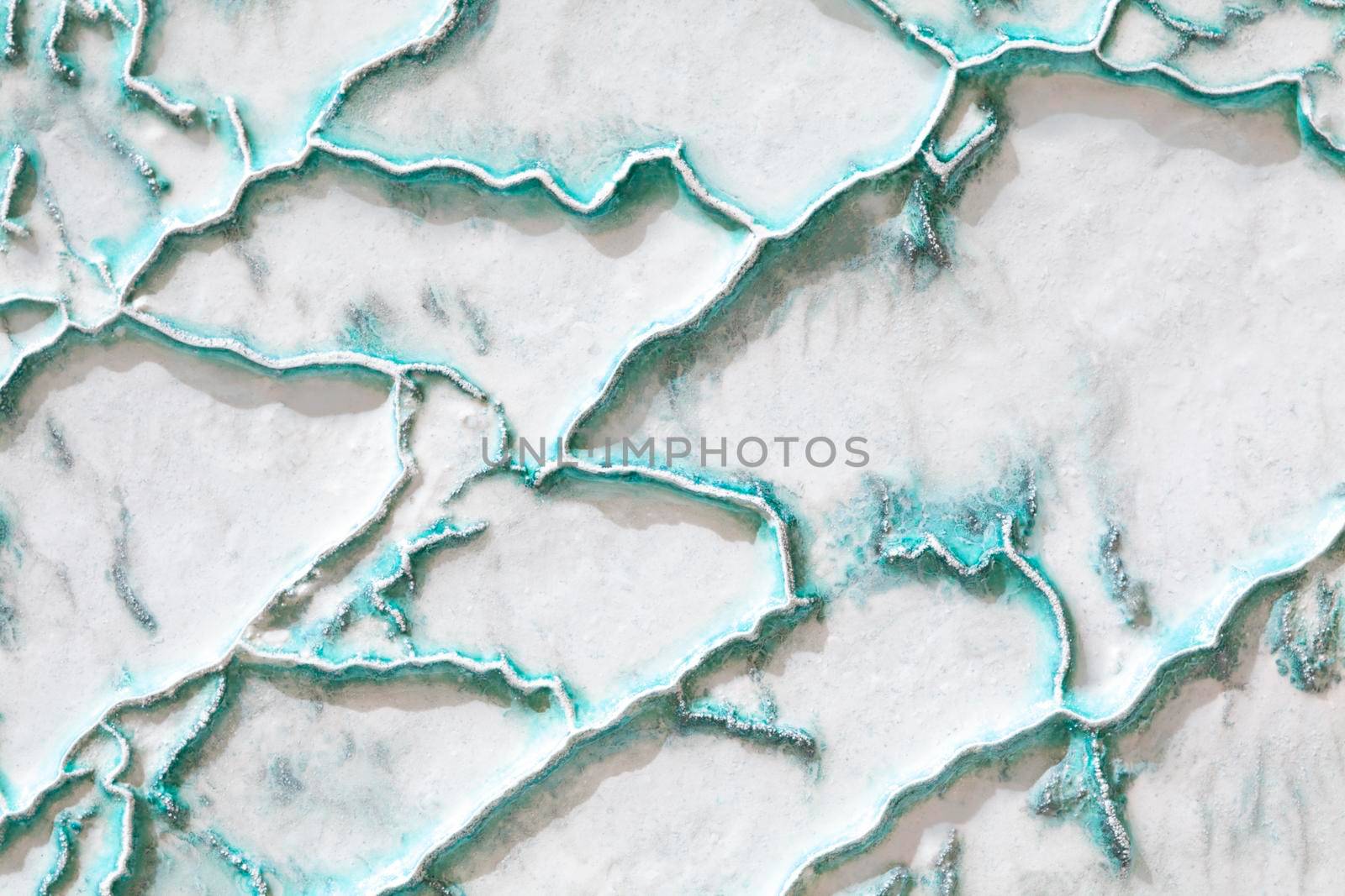 White-turquoise texture of Pamukkale calcium travertine in Turkey, uneven pattern of big cells
