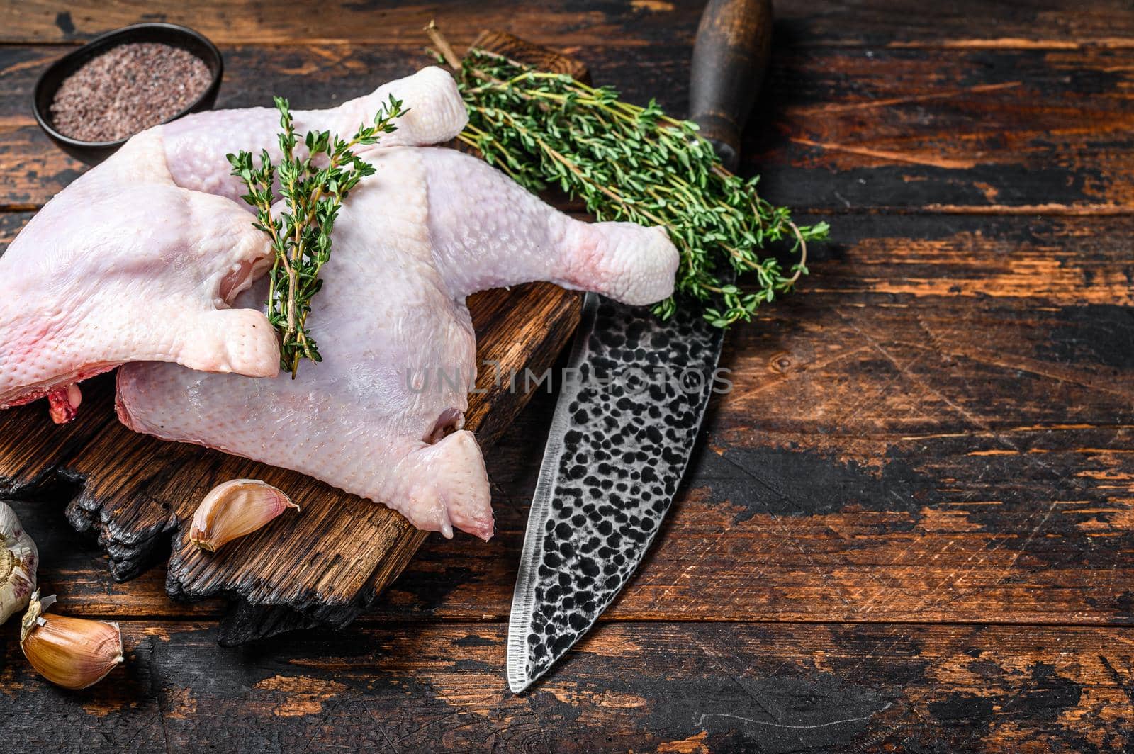 Raw chicken legs on a cutting board. Dark wooden background. Top view. Copy space by Composter