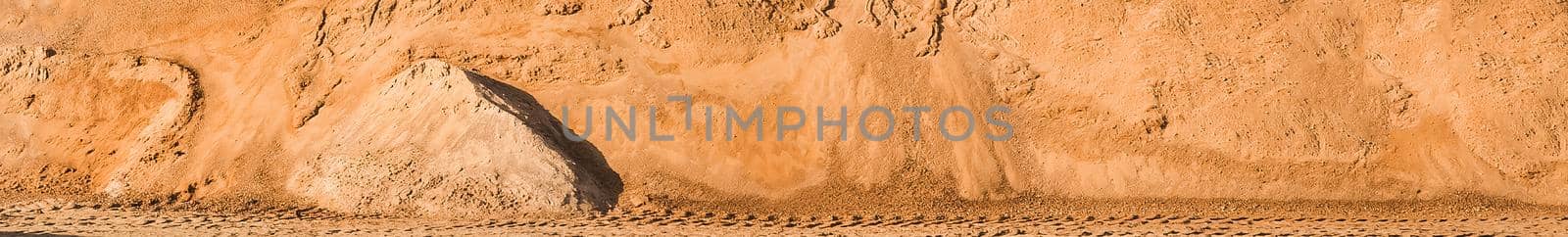 A large pile of sand in storage on industrial warehouse at a construction site.