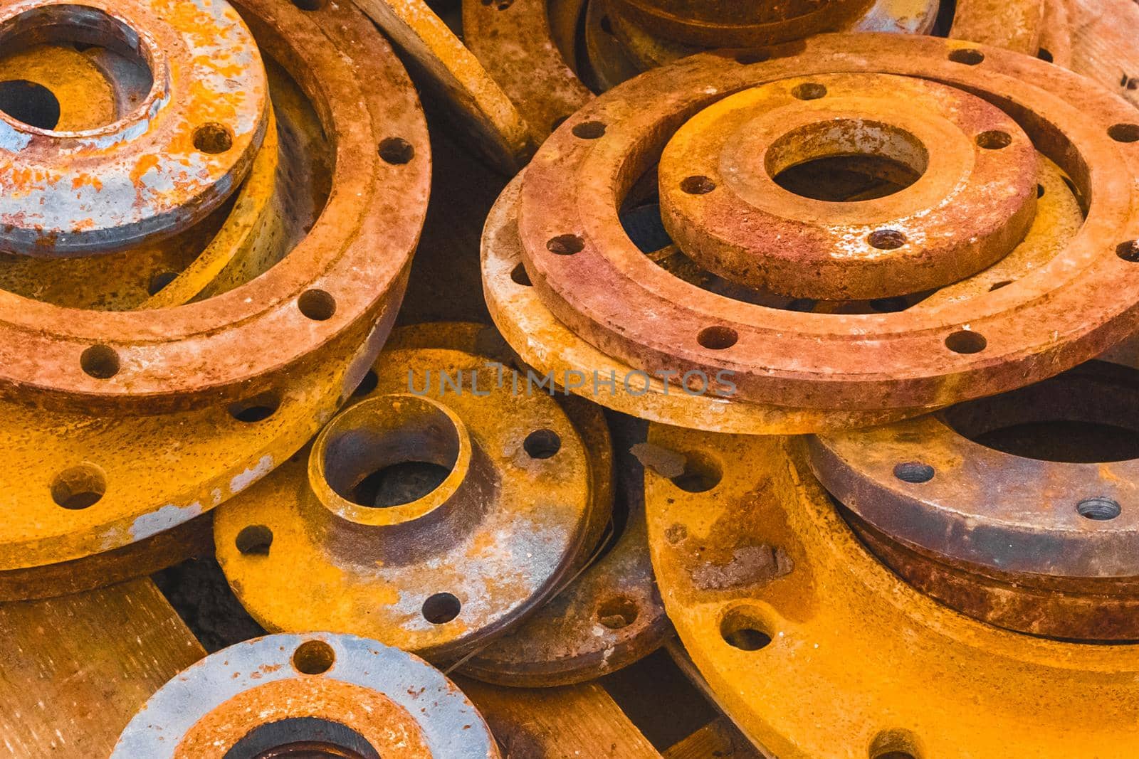 Pile of old, rusty pipe industrial flanges at a construction site.
