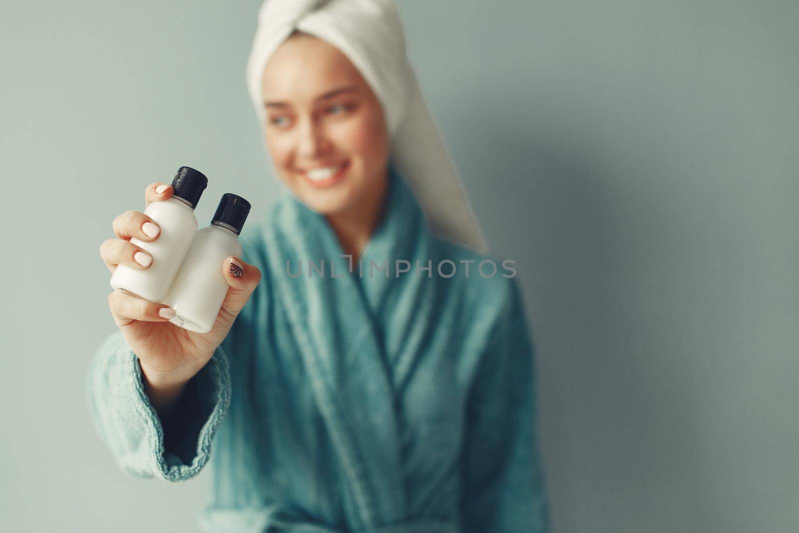 Girl in a studio. Lady with cream. Woman in a blue bathrobe