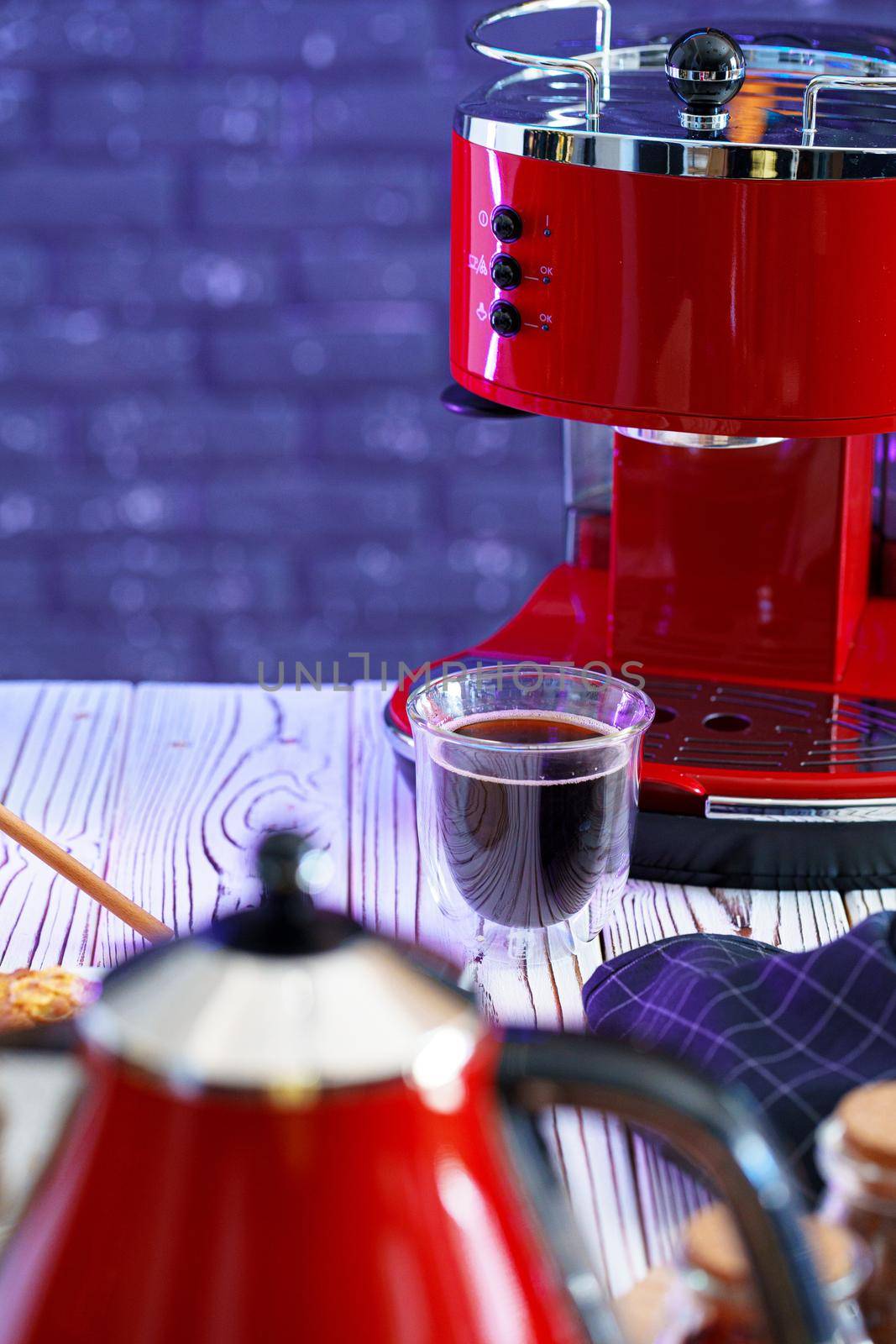 Red coffee machine with a glass on kitchen counter, close up