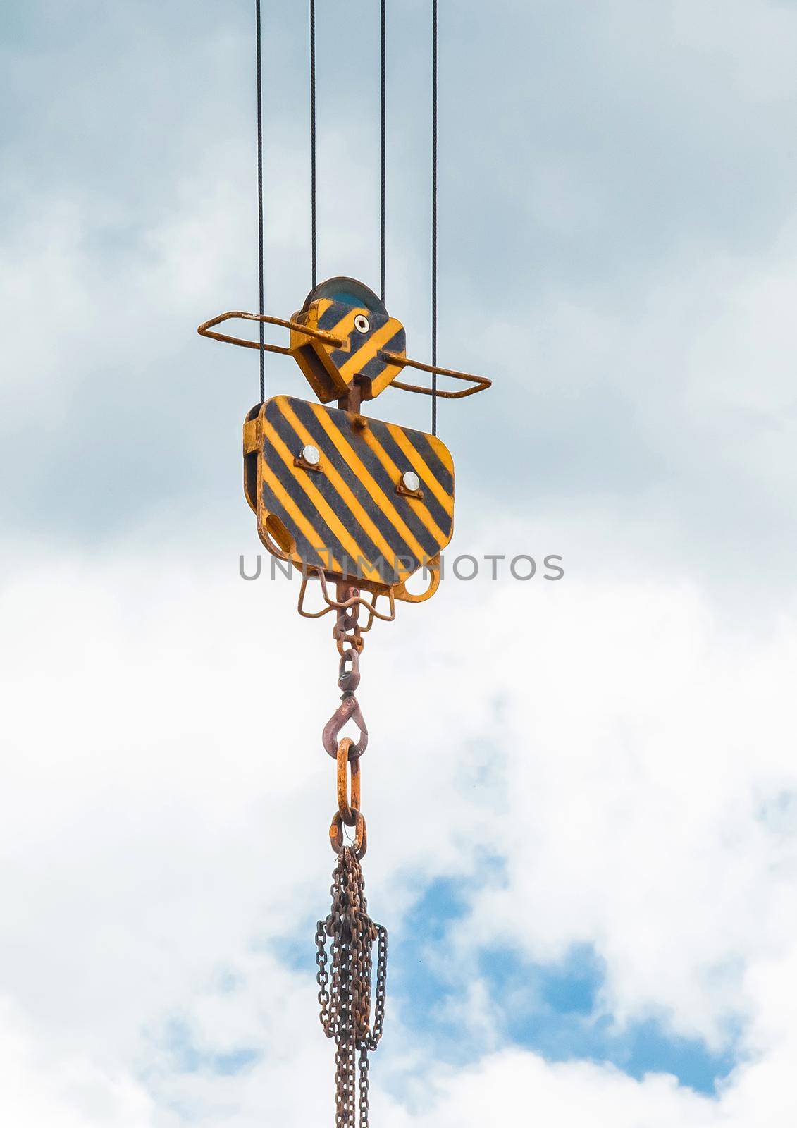 Hoisting heavy equipment lifting mechanism of a tower crane with a hook and chain against the sky. Close-up.