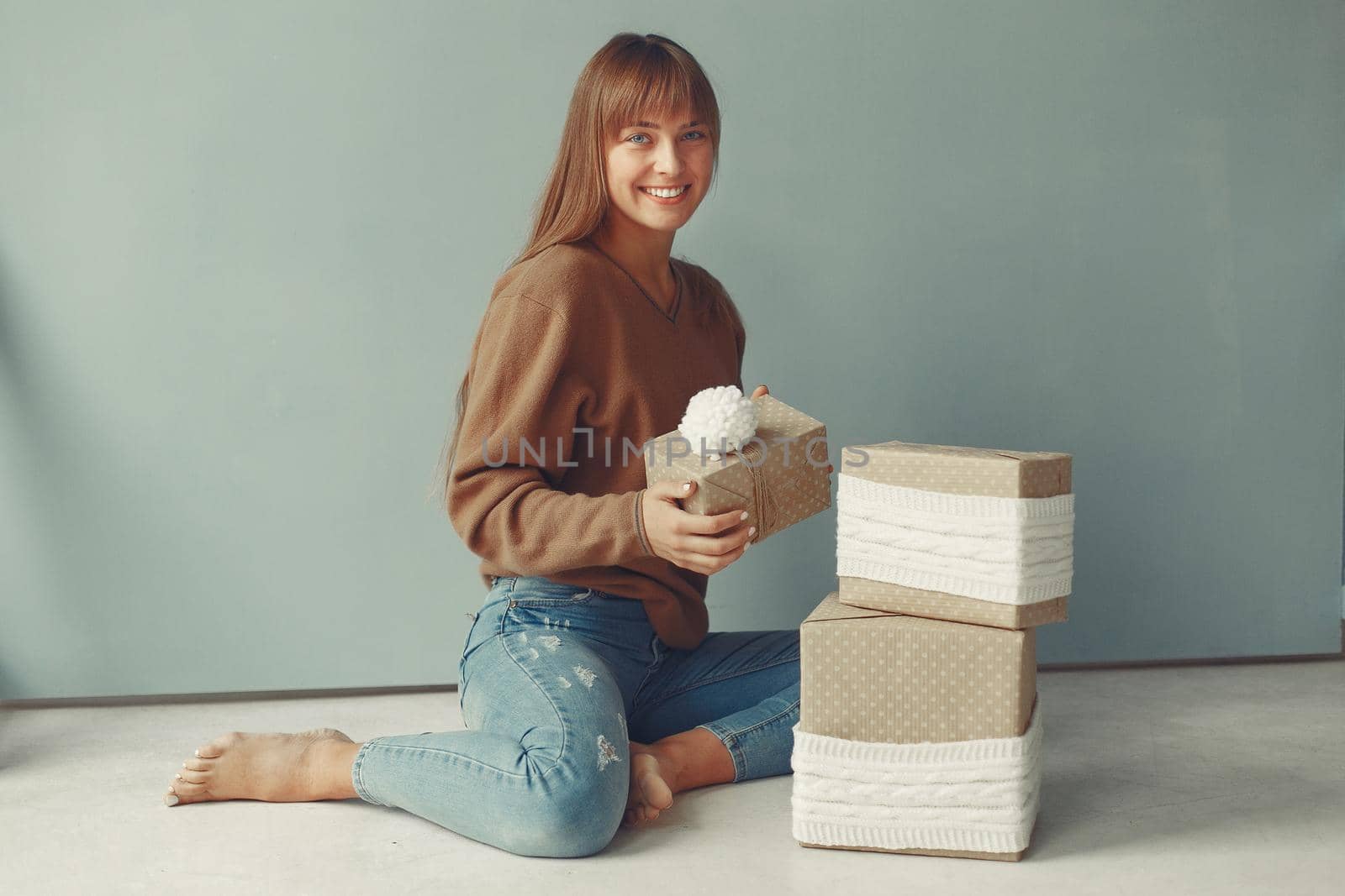 Woman with presents. Girl in a brown sweater. Lady in a studio.