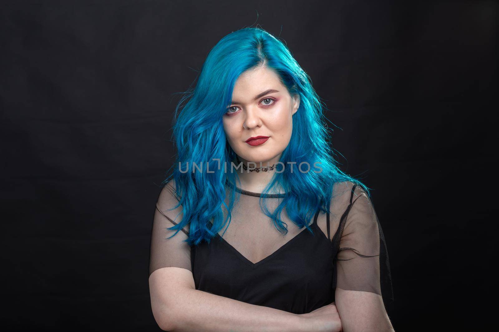 People and fashion concept - Close up portrait of woman with blue long hair over black background.