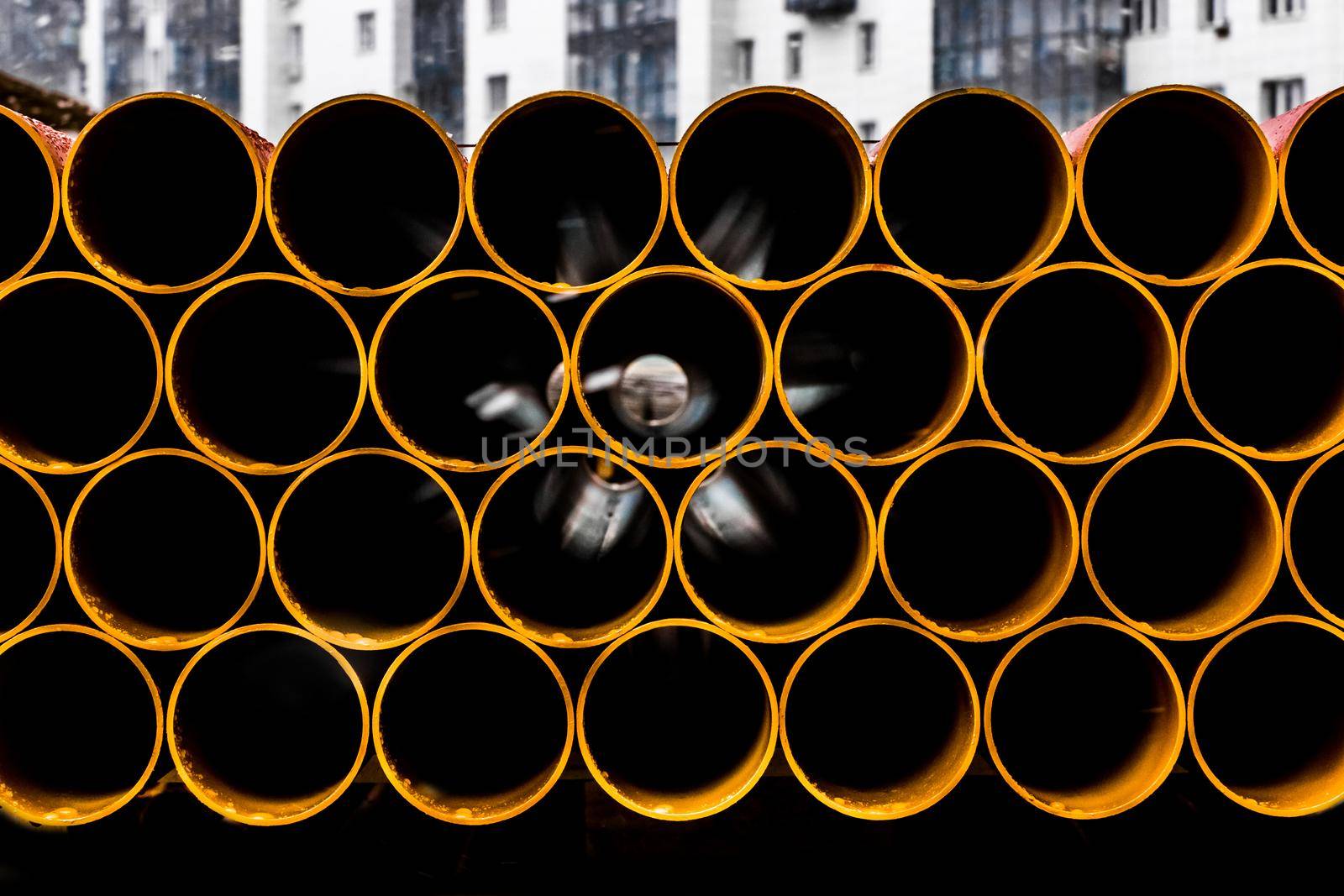 Pile of round industrial material polyethylene thermoplastic pipes on a construction site.