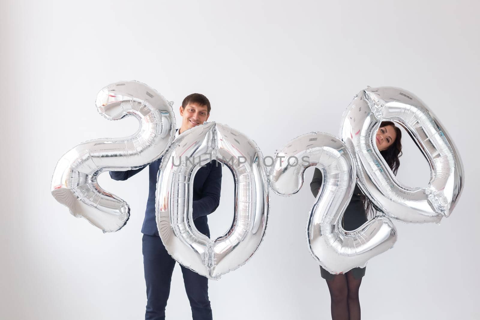 New year, celebration and holidays concept - love couple with sign 2020 made of silver balloons for new year on white background.