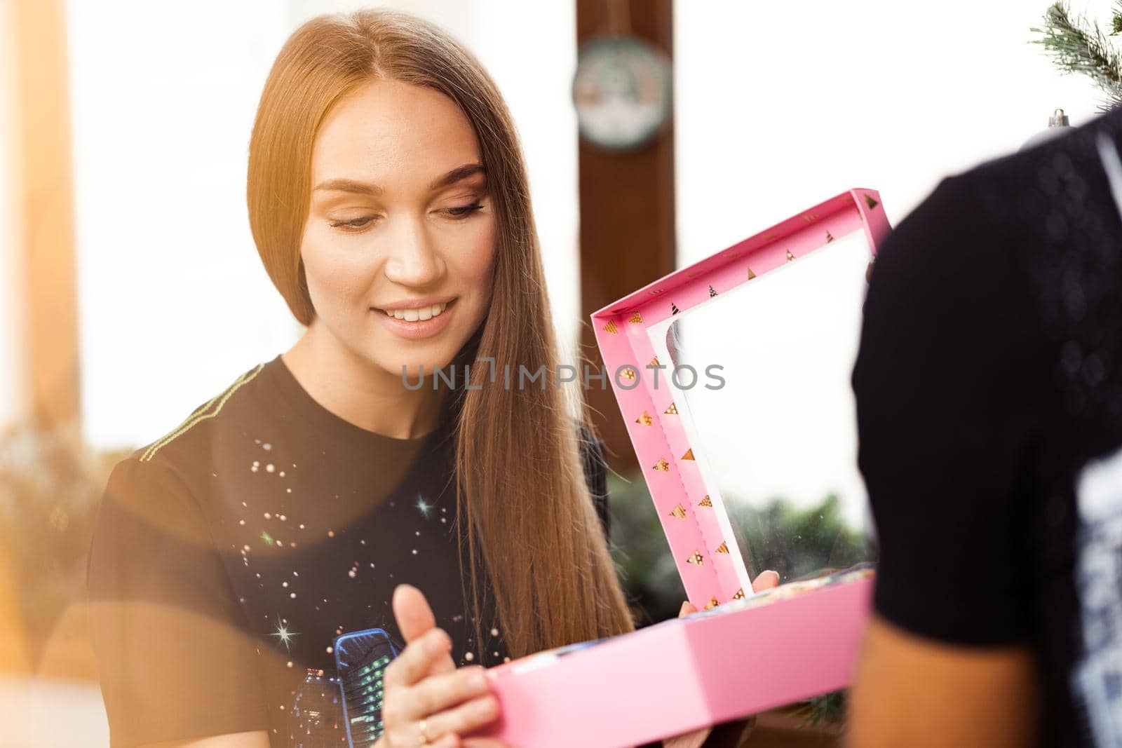 Surprised young woman opens a pink box with a present inside it