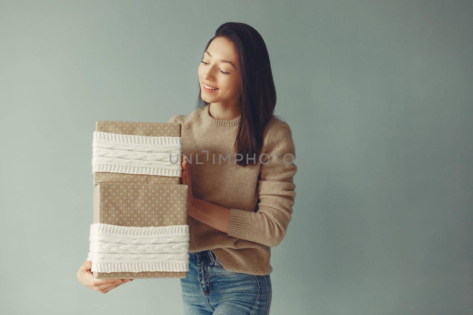 Woman with presents. Girl in a brown sweater. Lady in a studio.