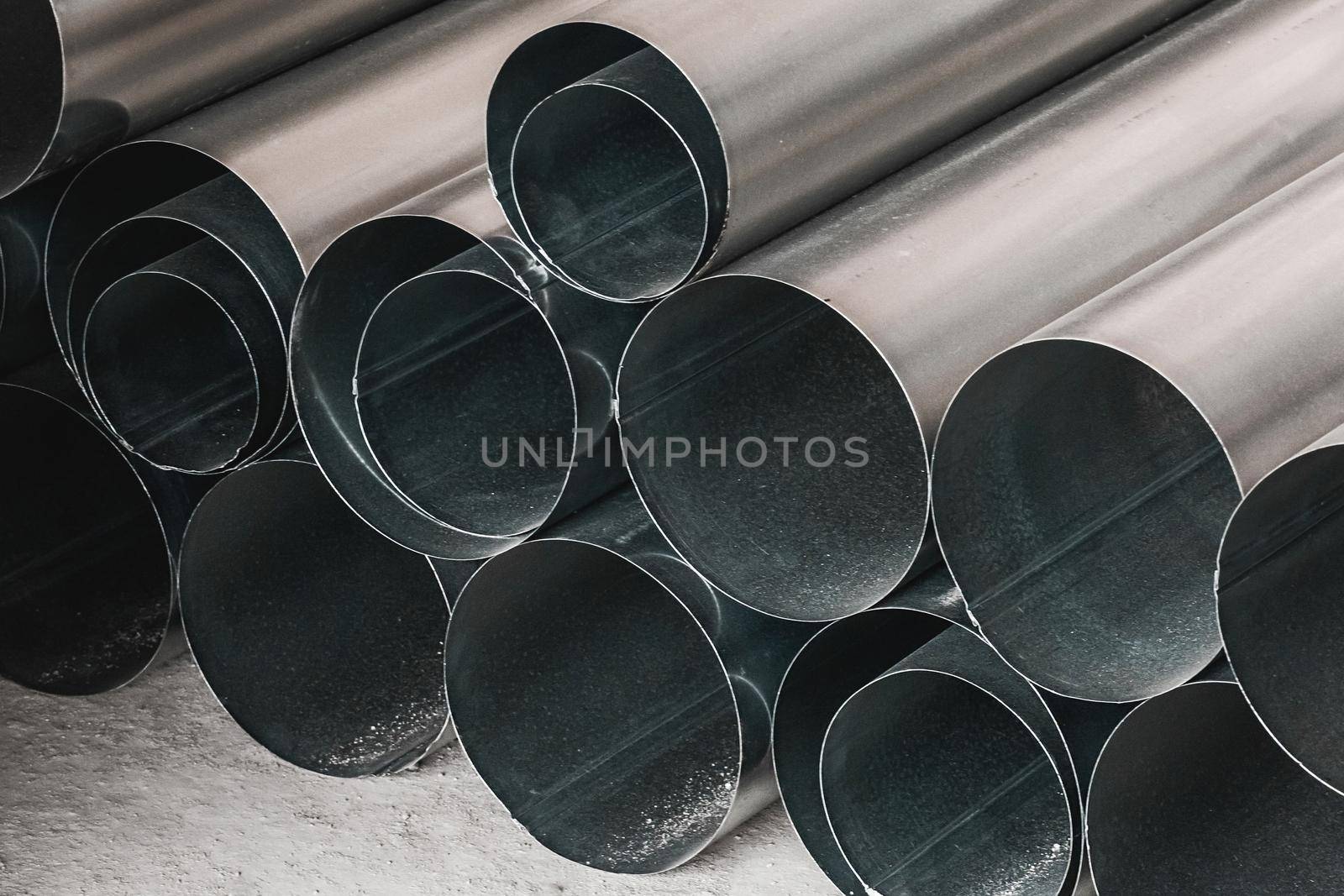 Pile of round metal pipes at a construction site. Storage steel tube industrial materials on warehouse.