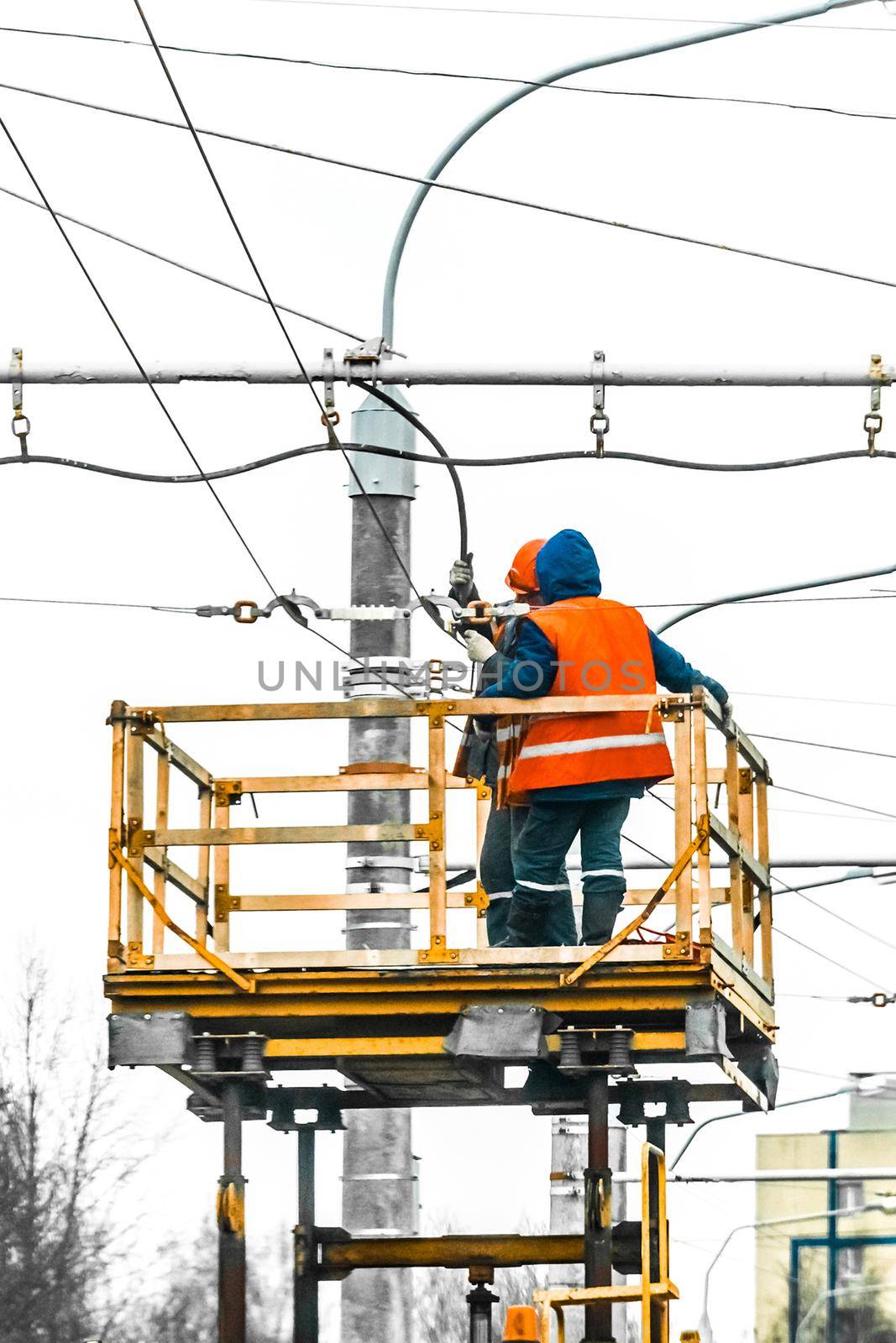 Two working men raised safety on a machine crane equipment mending a power electric line.