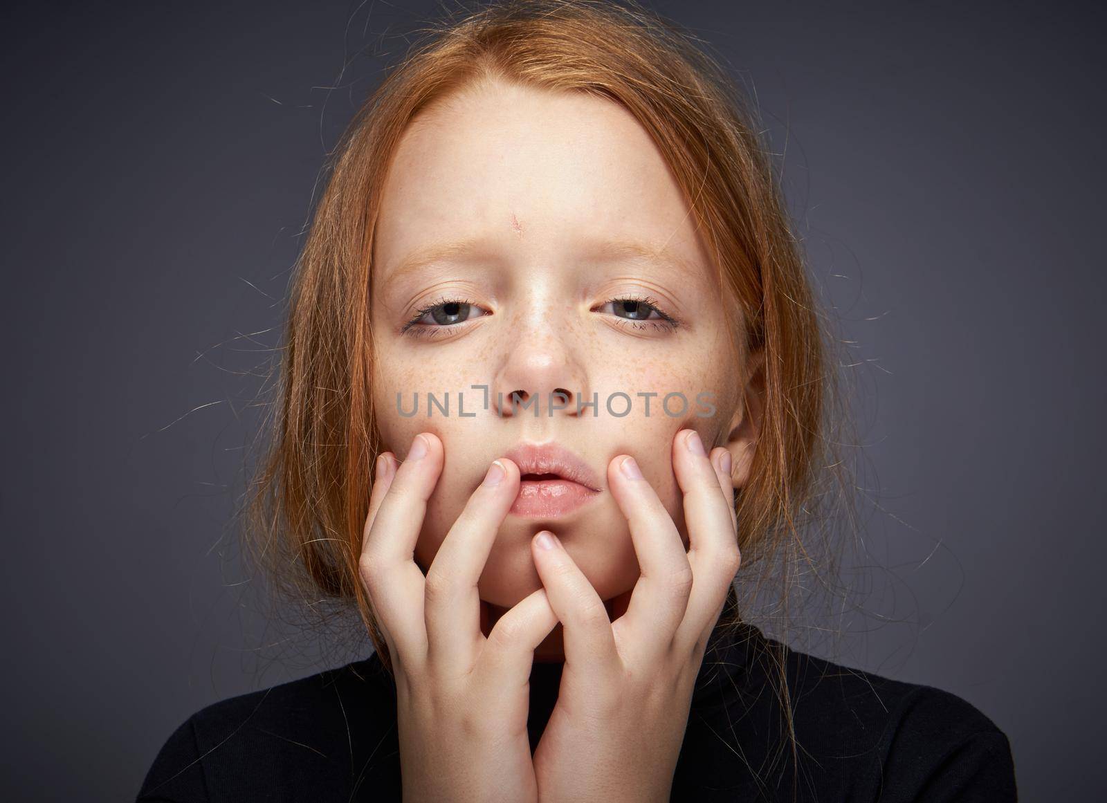 red-haired girl with freckles on her face in a black sweater posing. High quality photo