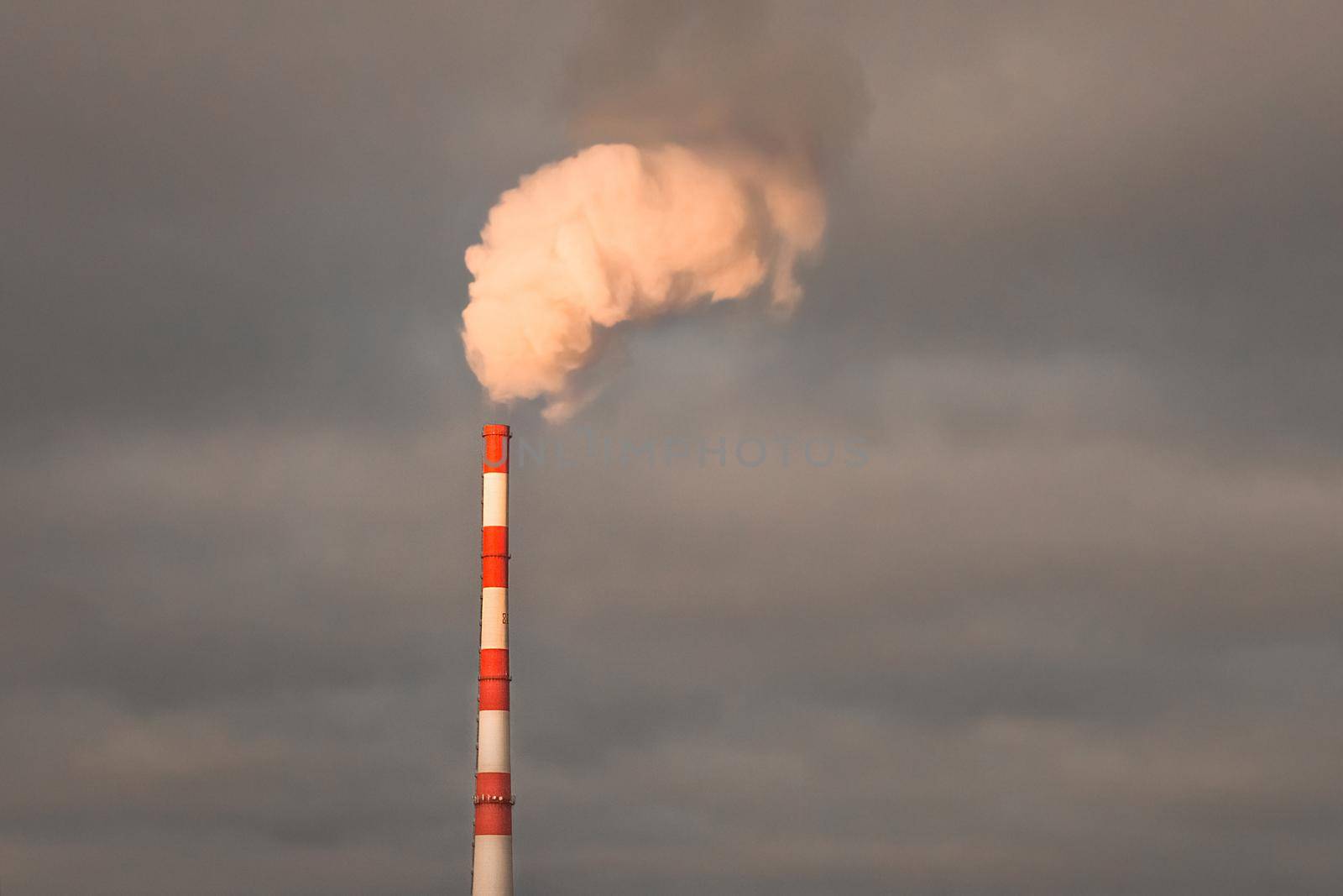 Environmental pollution problems and ecology concept. Smoke at sunset sky comes from a chimney of an industrial enterprise or thermal power plant and carbon dioxide is released into the atmosphere.