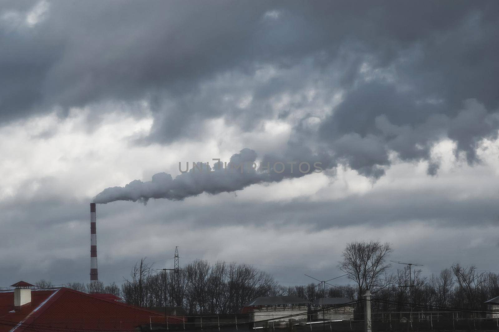 Environmental pollution, environmental problem, smoke from the chimney of a plant or thermal power plant against the dark grey sky.