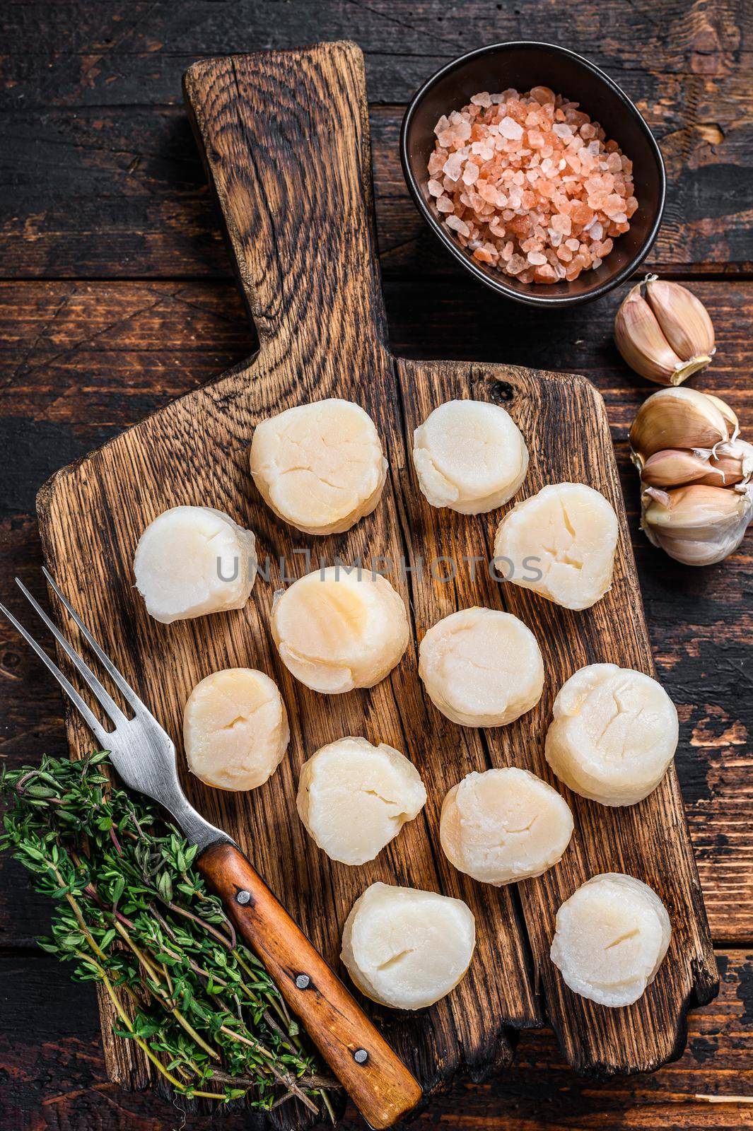 Steamed scallops meat on a wooden board. Dark wooden background. Top view.