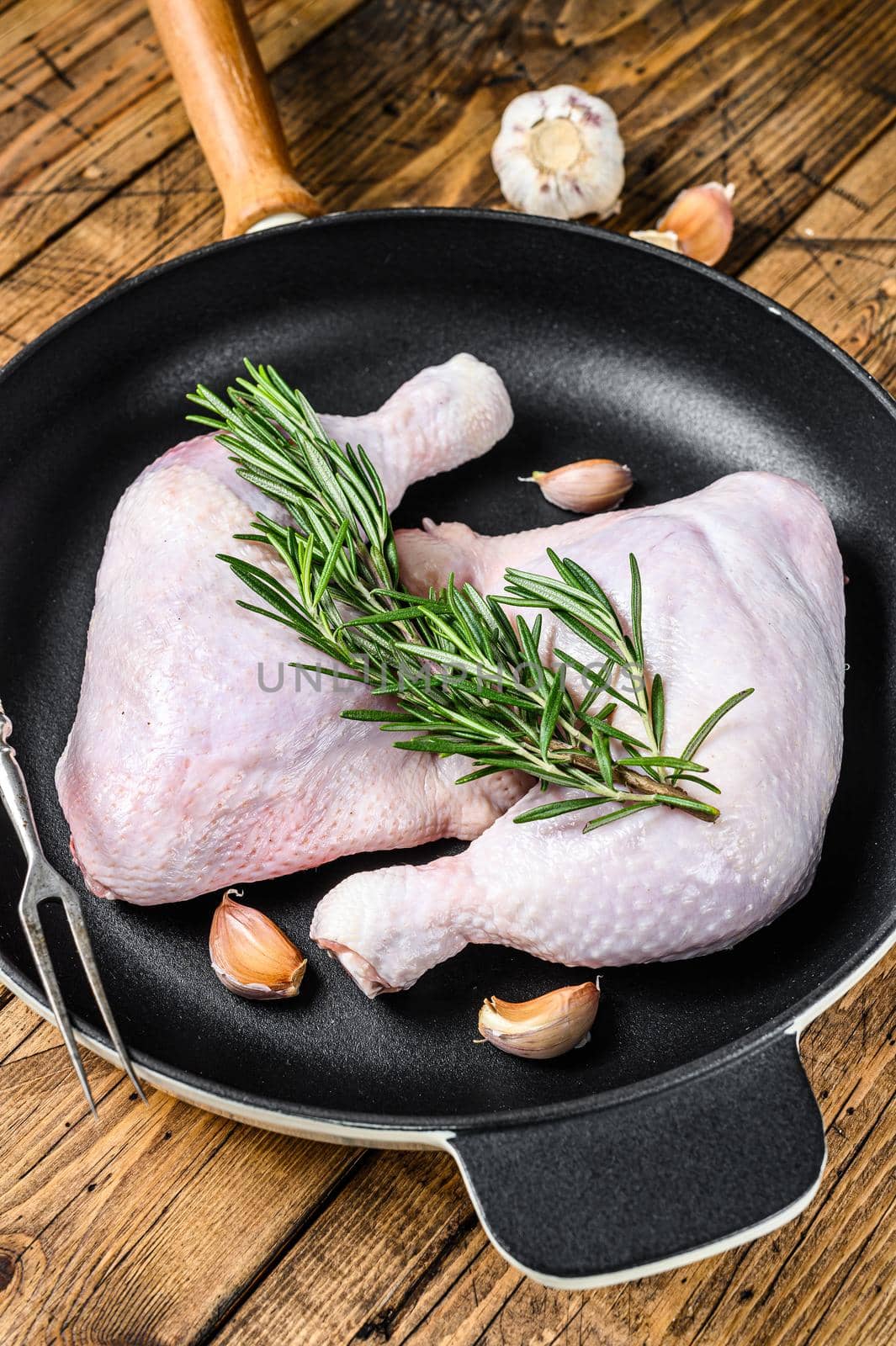 Raw chicken legs in a pan ready for the Grill. wooden background. Top view.