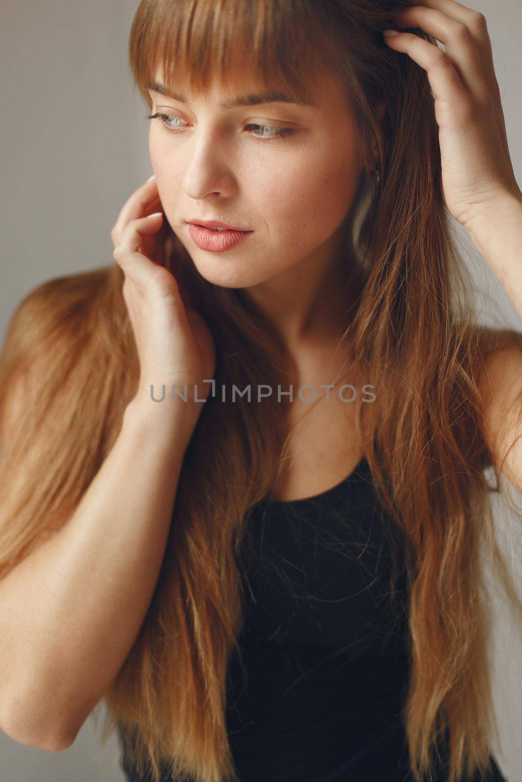 Beautiful girl in a studio. Stylish girl near gray wall. Lady in a black t-shirt