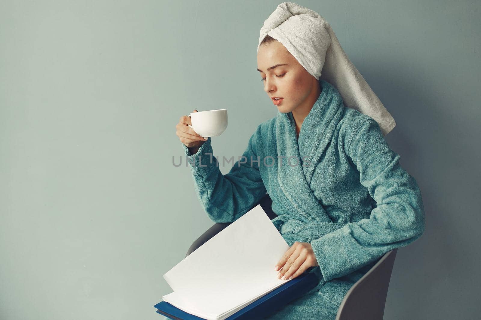 Girl in a studio. Lady in a blue bathrobe. Woman with a documents