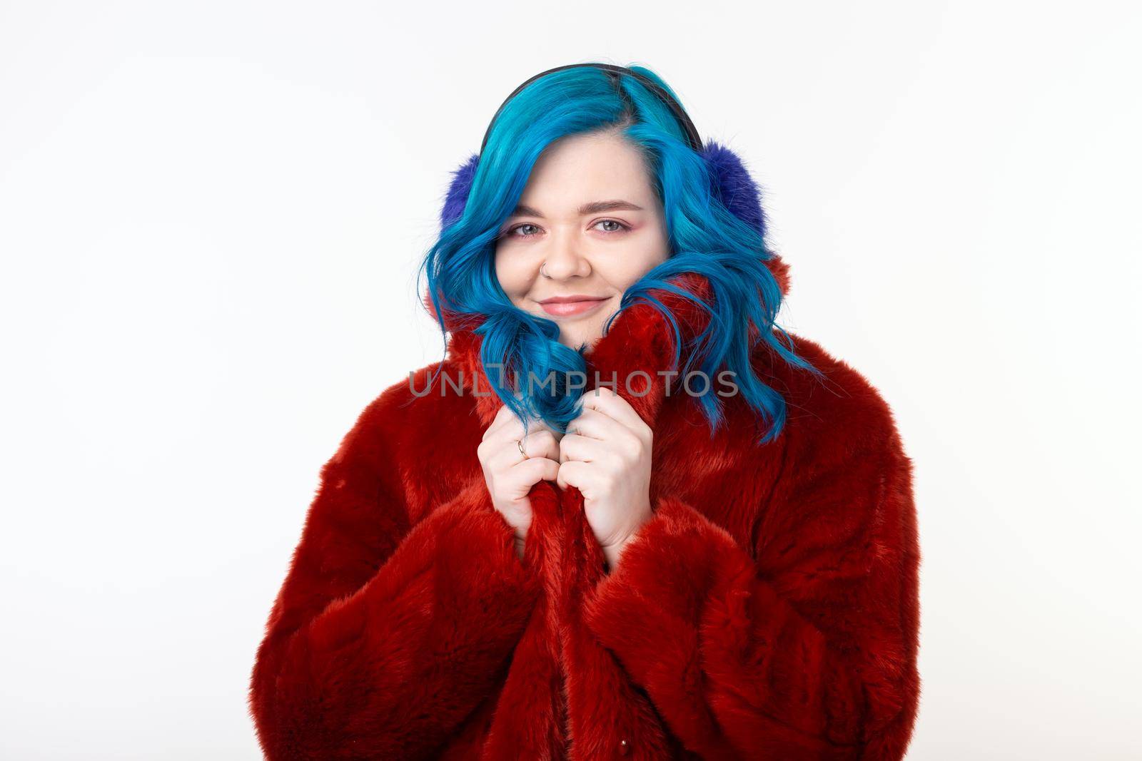 People, protection animals and fashion concept - Beautiful girl with blue hair dressed in red warm jacket in artificial fur and earmuffs.