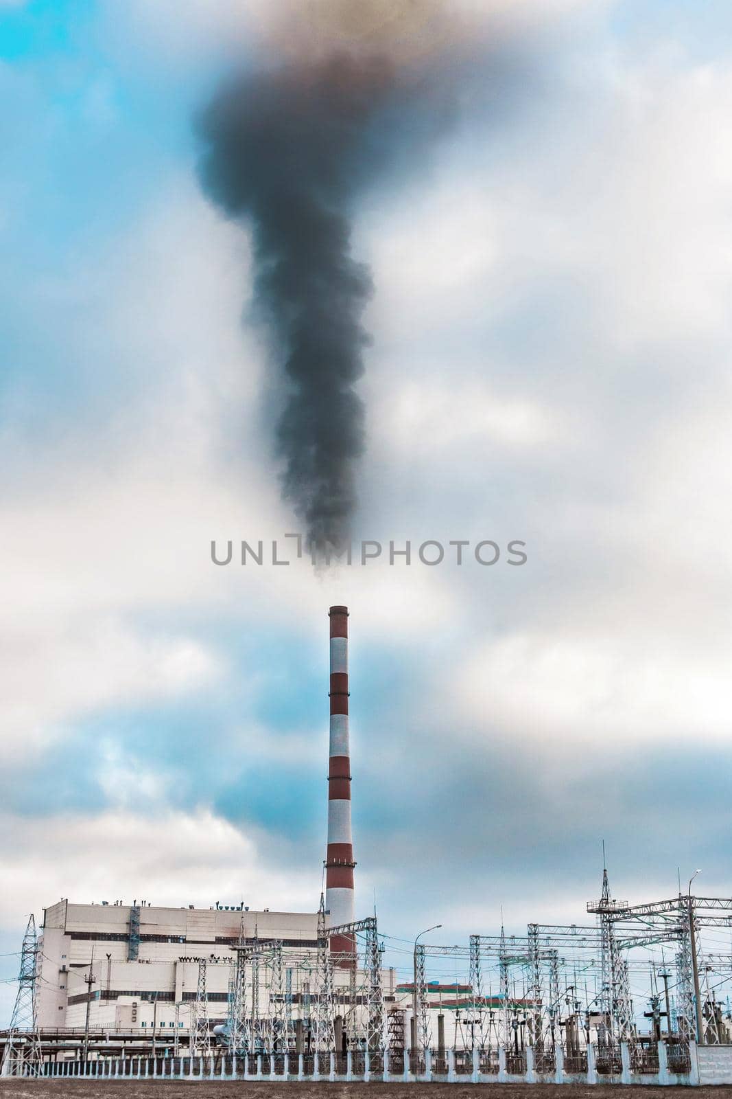 Environmental problem, environmental pollution, smoke from the pipe of an thermal power plant against a blue sky.