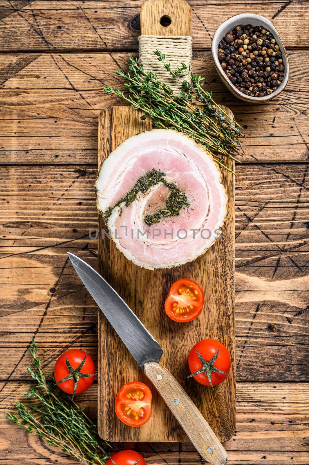 Italian traditional bacon pancetta on a cutting board. Wooden background. Top view.