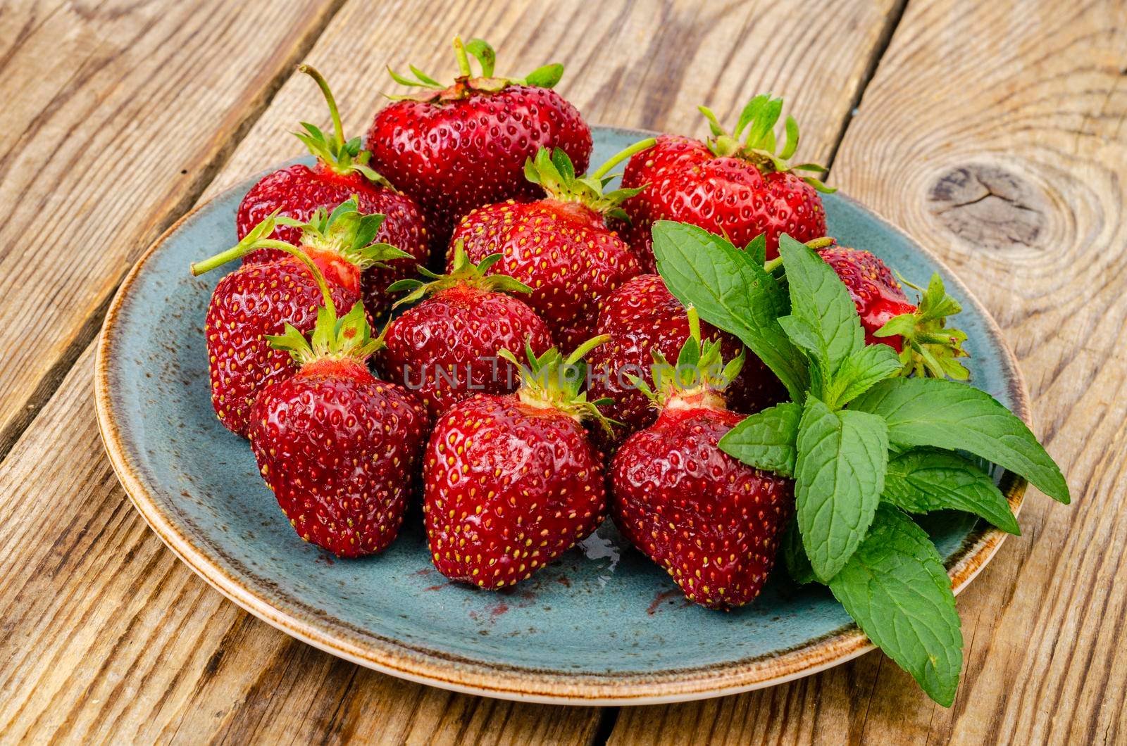 Red ripe strawberries on blue plate. Photo by ArtCookStudio