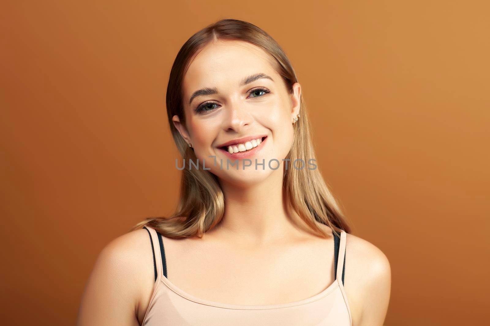 young pretty blond woman with fresh natural makeup posing cheerful on browm background, lifestyle people concept closeup