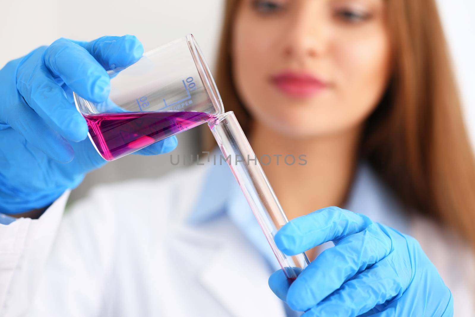 Female chemist holds test tube of glass in his hand overflows a liquid solution of potassium permanganate conducts an analysis reaction takes various versions of reagents using chemical manufacturing