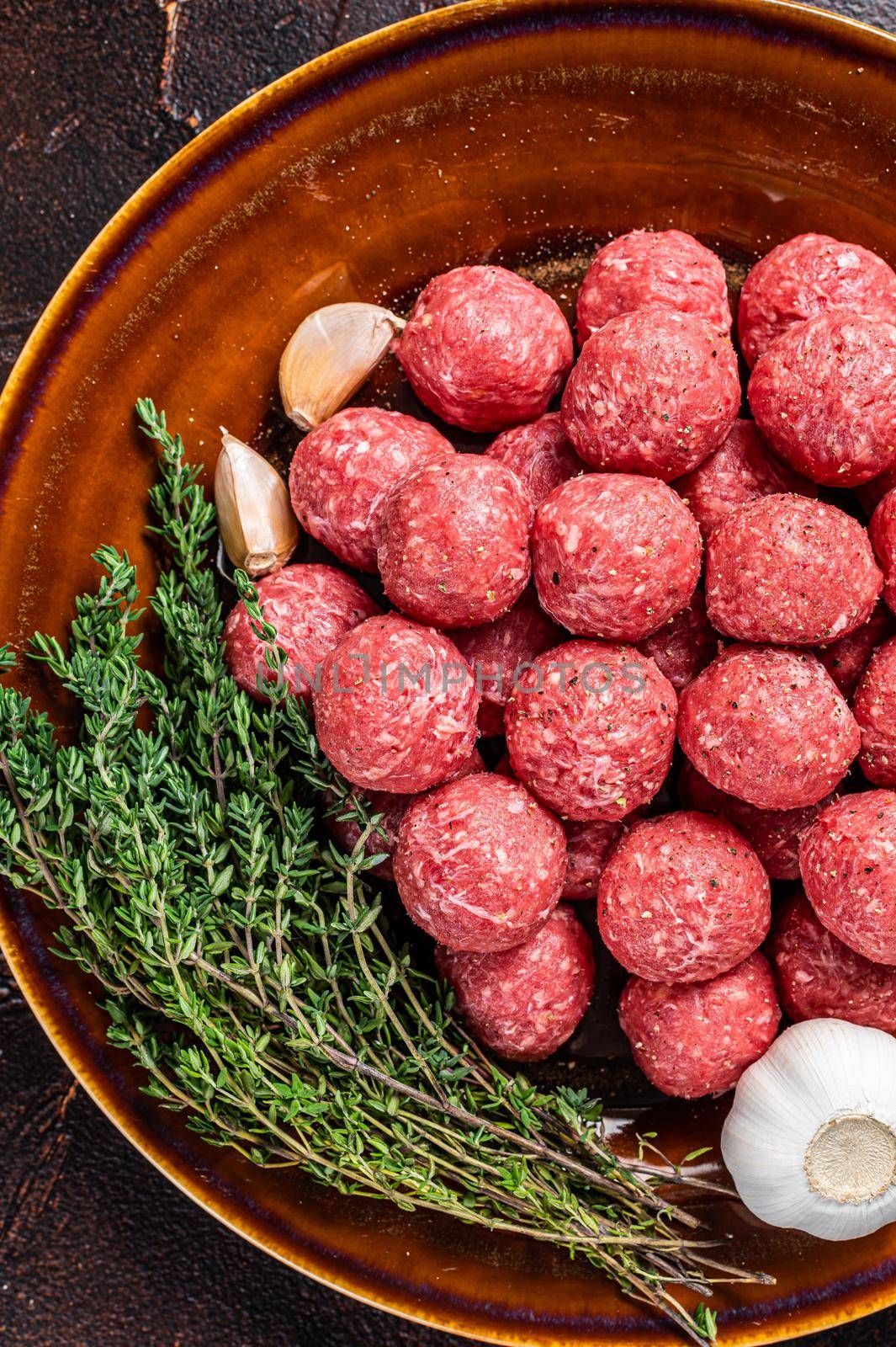 Fresh Raw meatballs from mince beef and pork meat with thyme. Dark background. Top view.