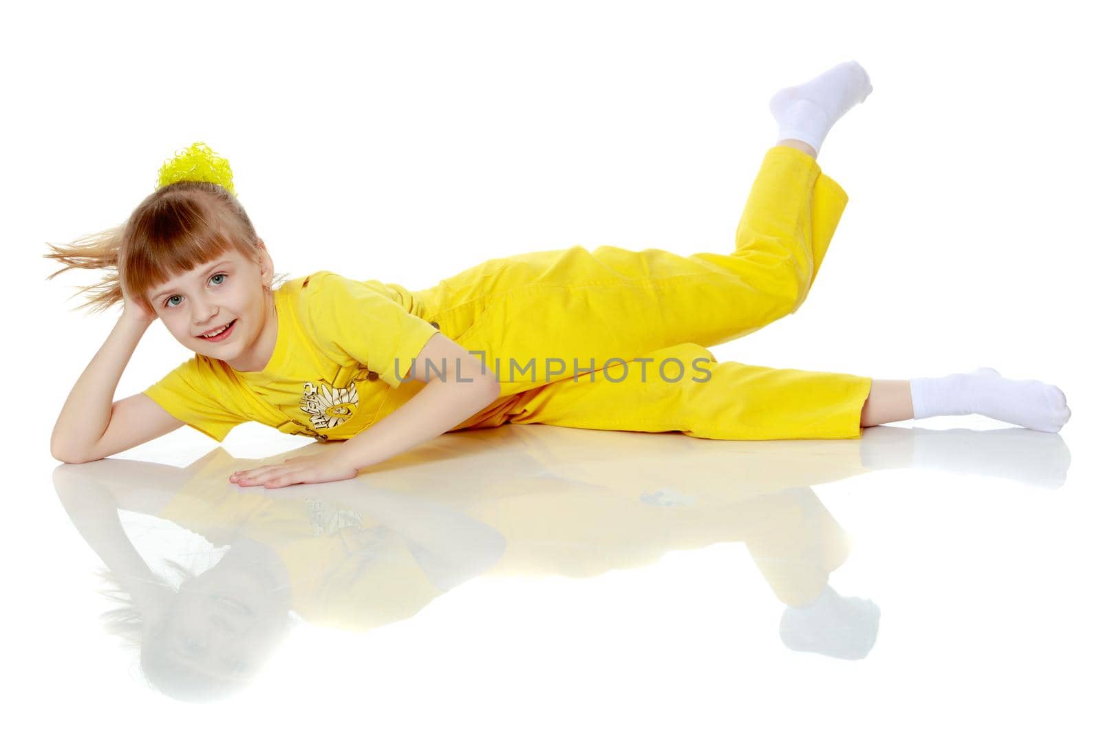 Girl with a short bangs on her head and bright yellow overalls.She crouched down on the white advertising banner.