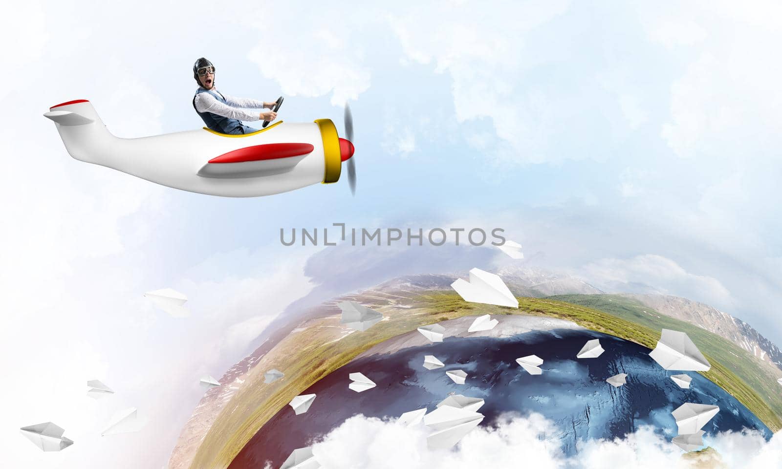 Pilot in leather helmet driving propeller plane on background of blue cloudy sky. Traveling around the world by airplane. Funny man flying in small airplane. Earth horizon with mountains and ocean