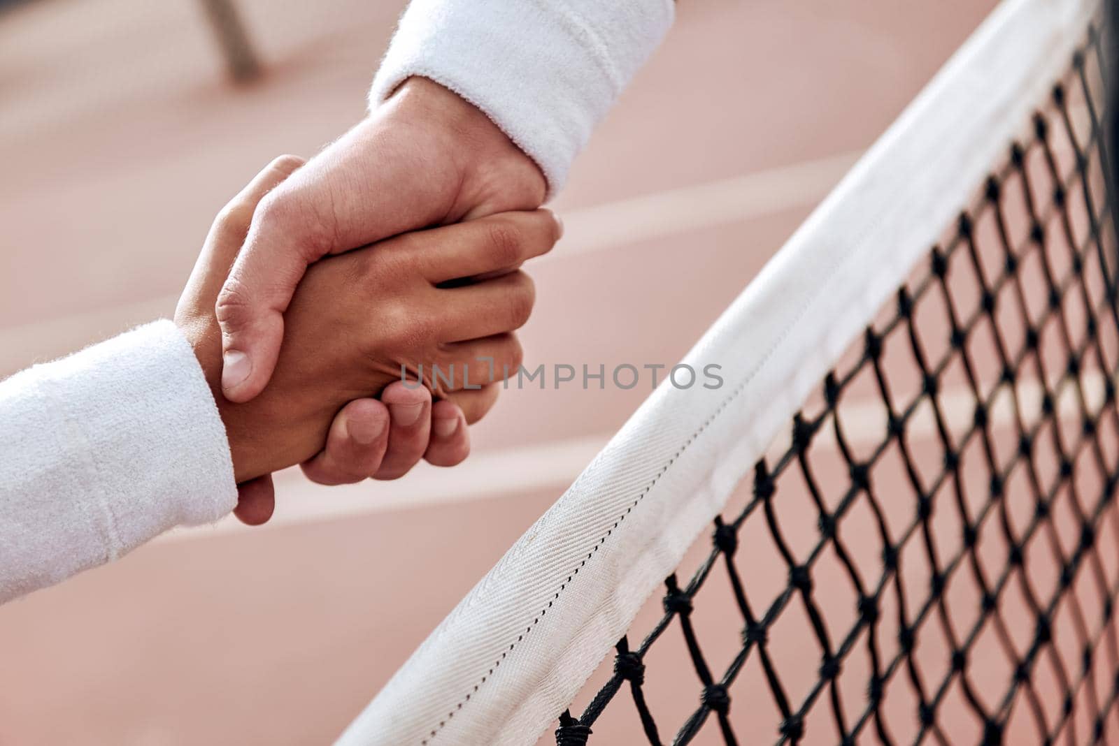 Two tennis players are shaking hands by friendsstock
